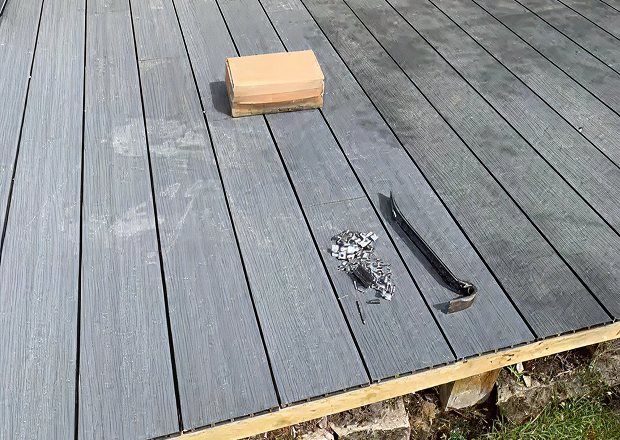 Installing composite decking with box clips and crowbar on the deck