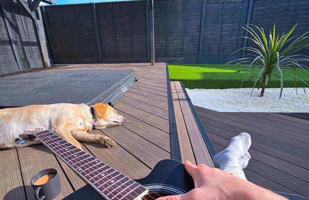 Walnut Composite Decking With Dog Laid Down With Hot tub & Guitar