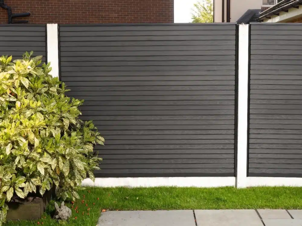 Slatted Composite Fence Panels in Black With Grass & Paving